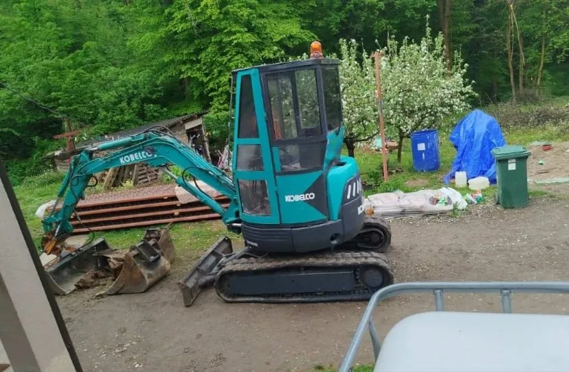Mini bager Kobelco sa kašikama različitih širina u dvorištu