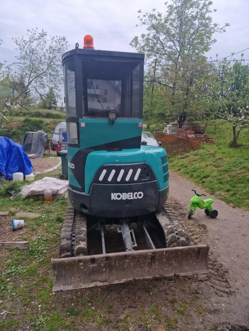 Mini bager u dvorištu porodične kuće pre iskopa za septičku jamu